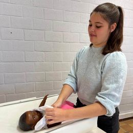 Leerling maatschappij en welzijn verschoont baby tijdens de les